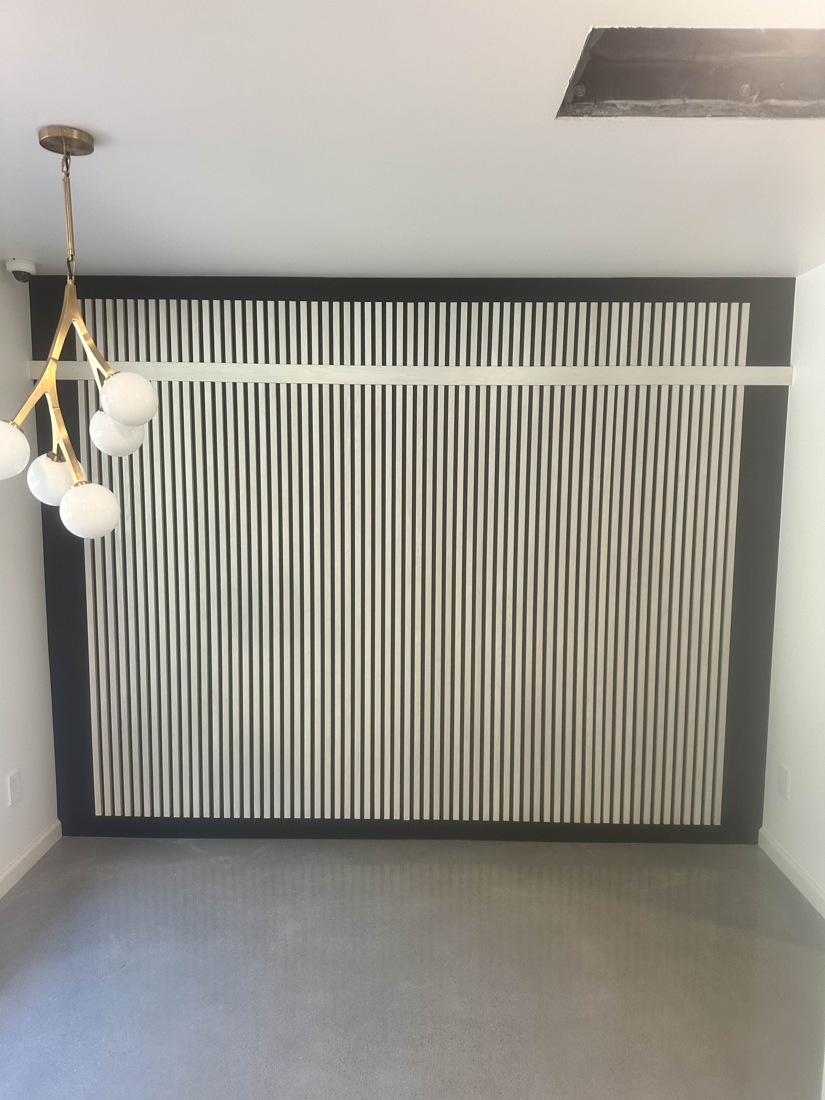 Hidden room concealed behind ribbed wall paneling with brass pendant lighting