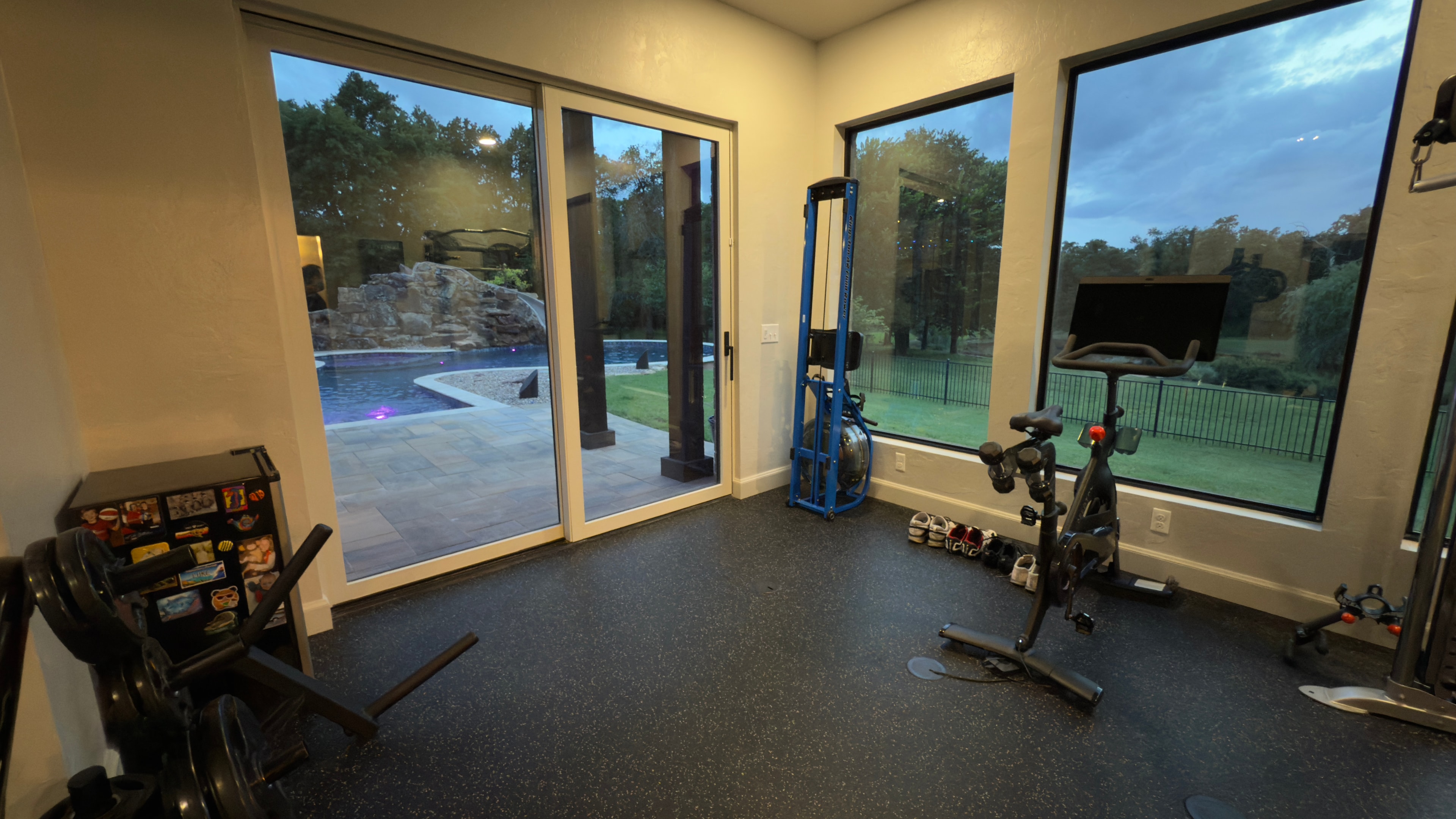 Home gym with floor-to-ceiling windows overlooking resort-style pool and grotto