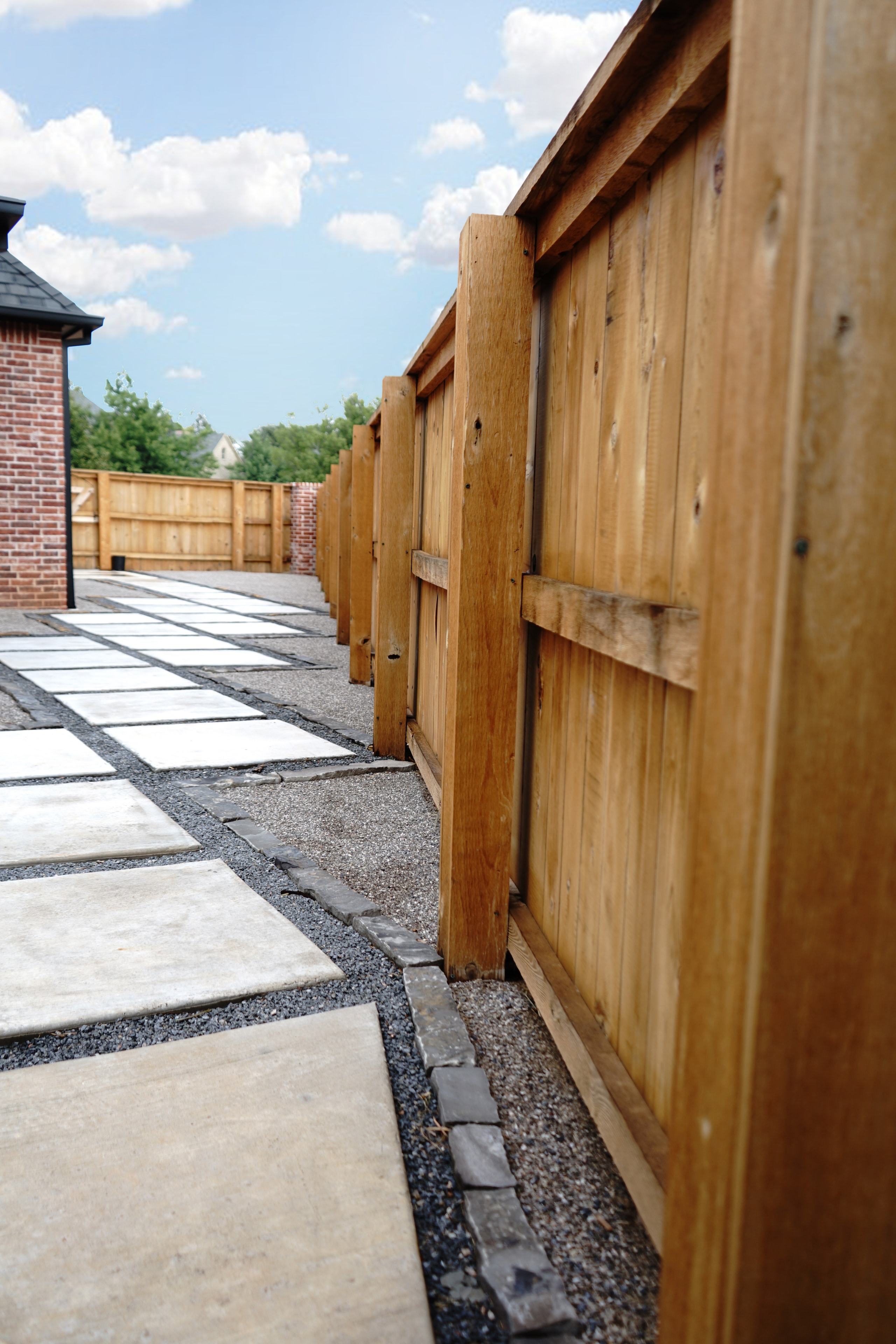 Concrete paver stepping-stone path with gravel and cedar privacy fence