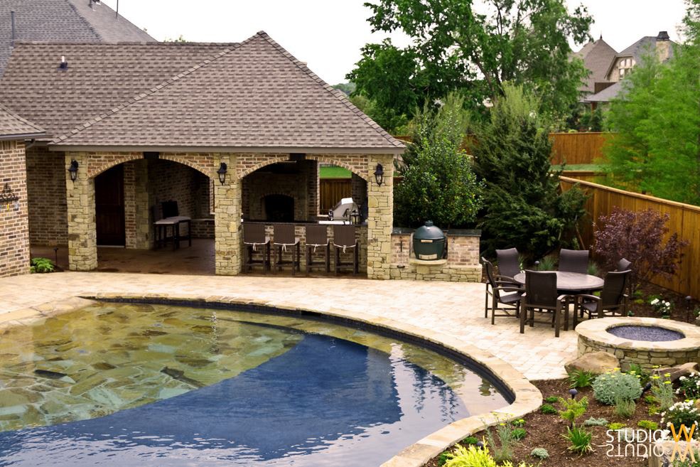 Stone arch outdoor kitchen with Big Green Egg, fire pit, and freeform pool patio